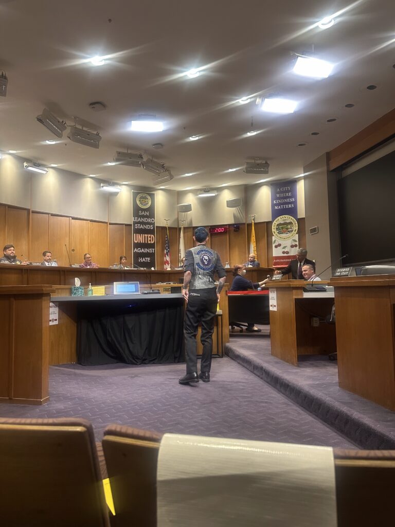 Willow checking in at city chambers. There is a flag in the background that reads "San Leandro stands united against hate" and "A city where kindness matters"