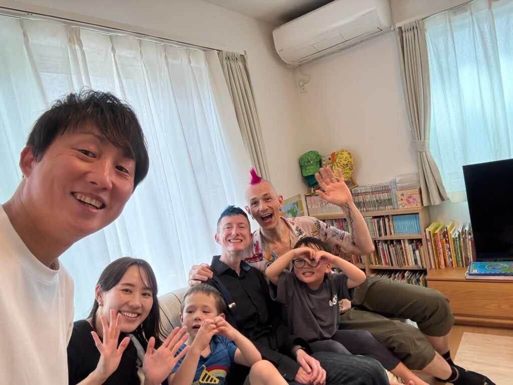 Chiaki, Shu, Riktoh, and us wave from a couch in a selfie. 